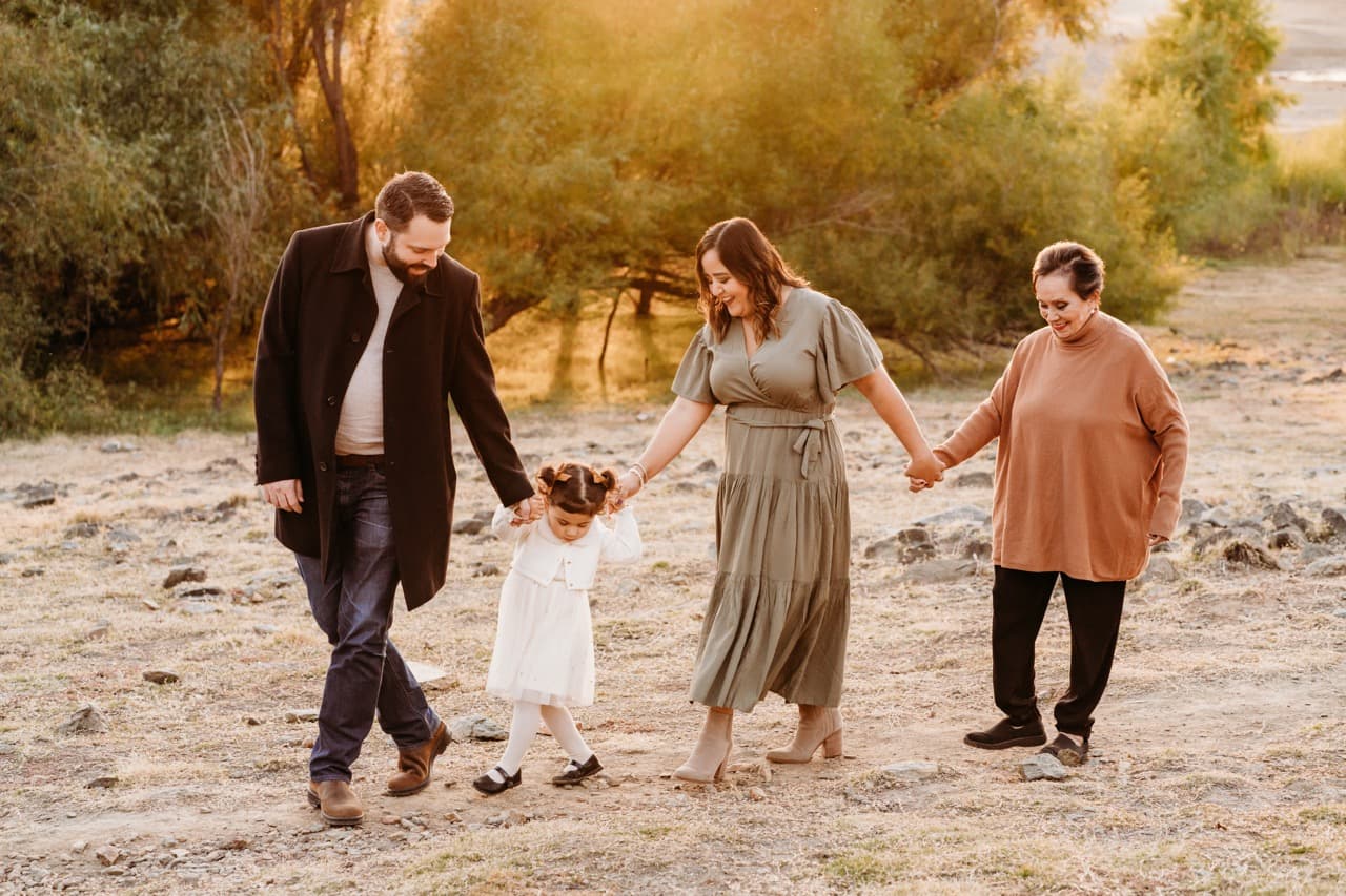 Three generations walking hand in hand through a golden field