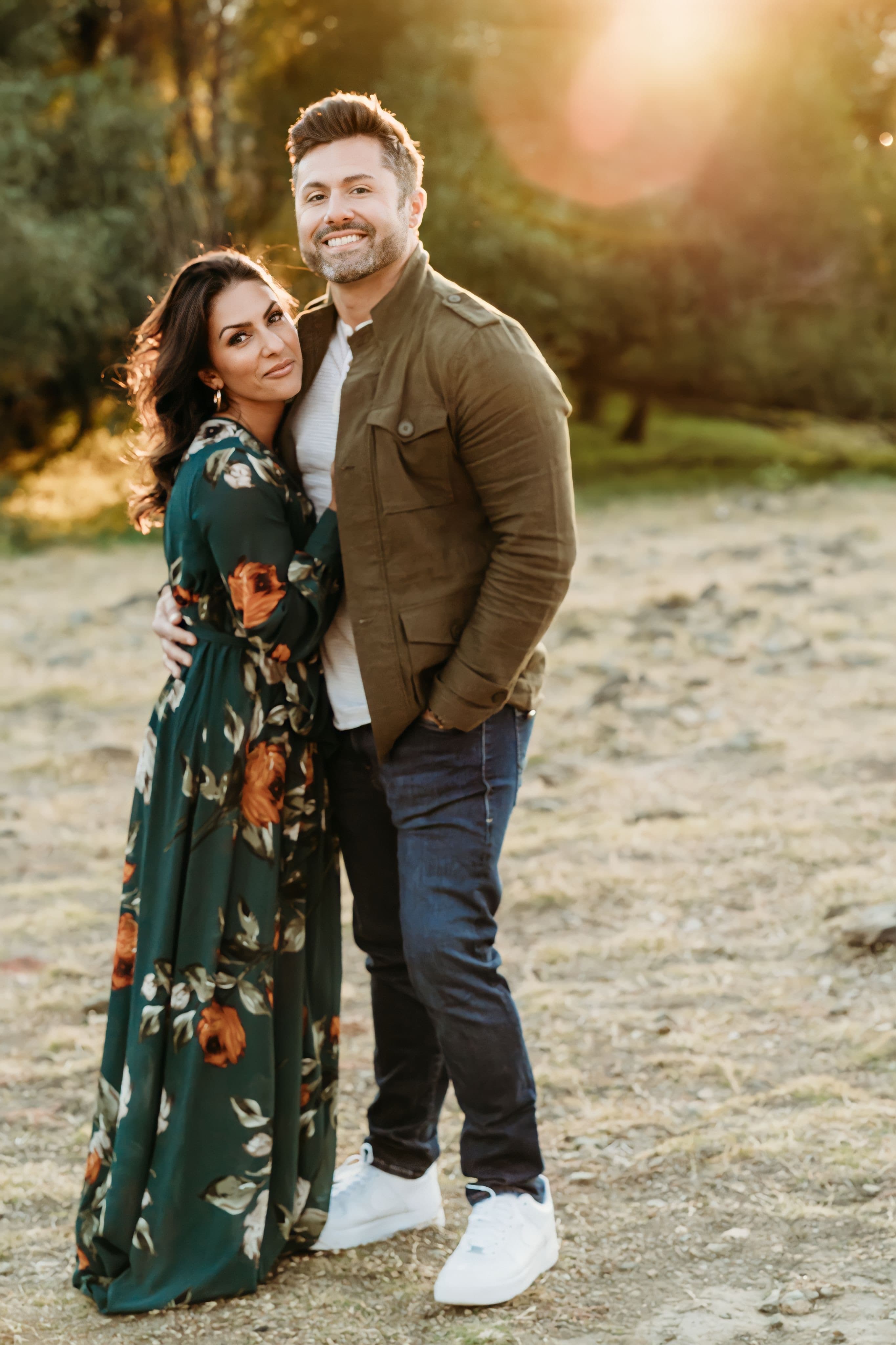 Couple embraces in a golden field, she in a green floral dress