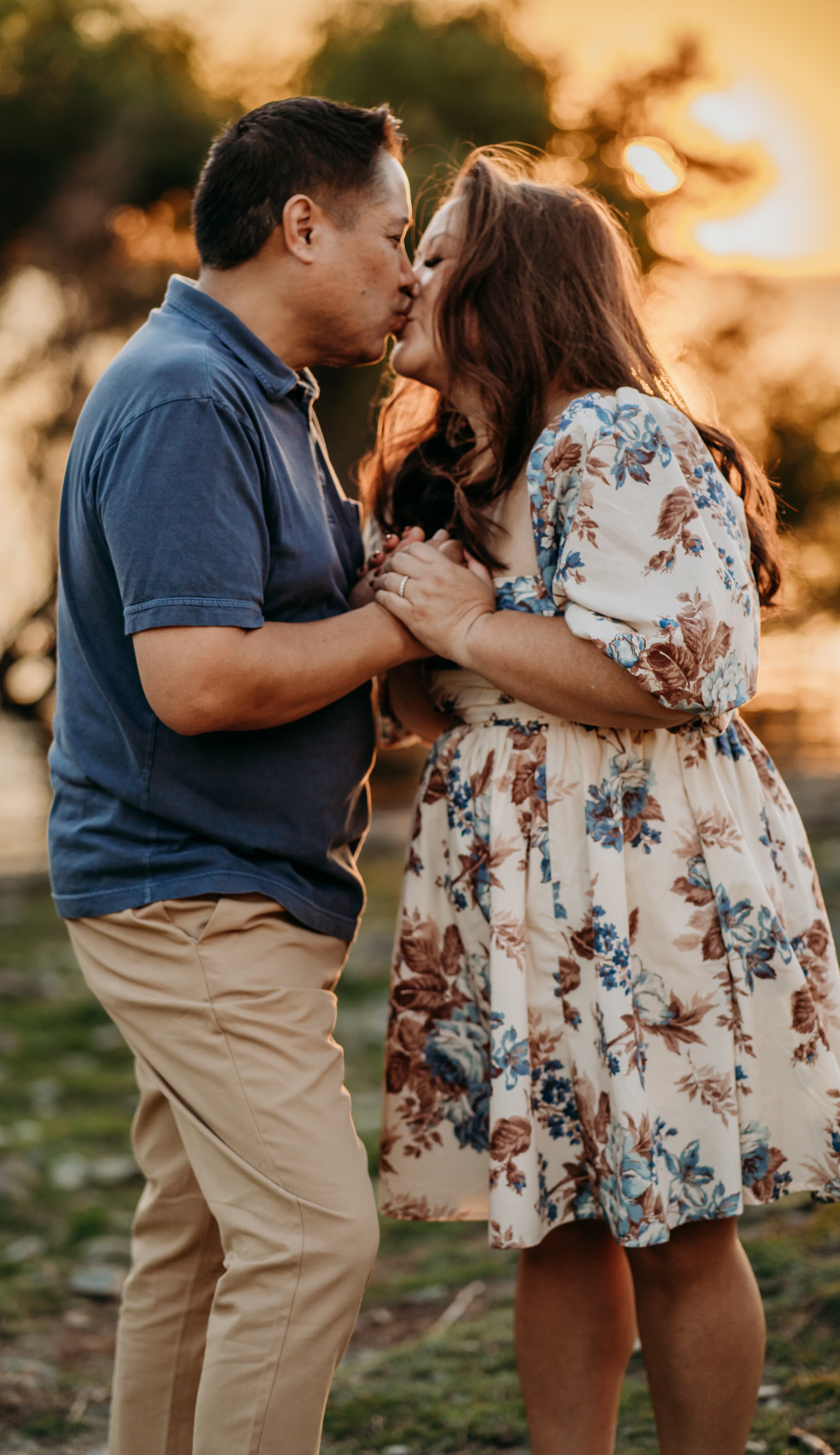 Couple shares a kiss backlit by golden-hour sunset light