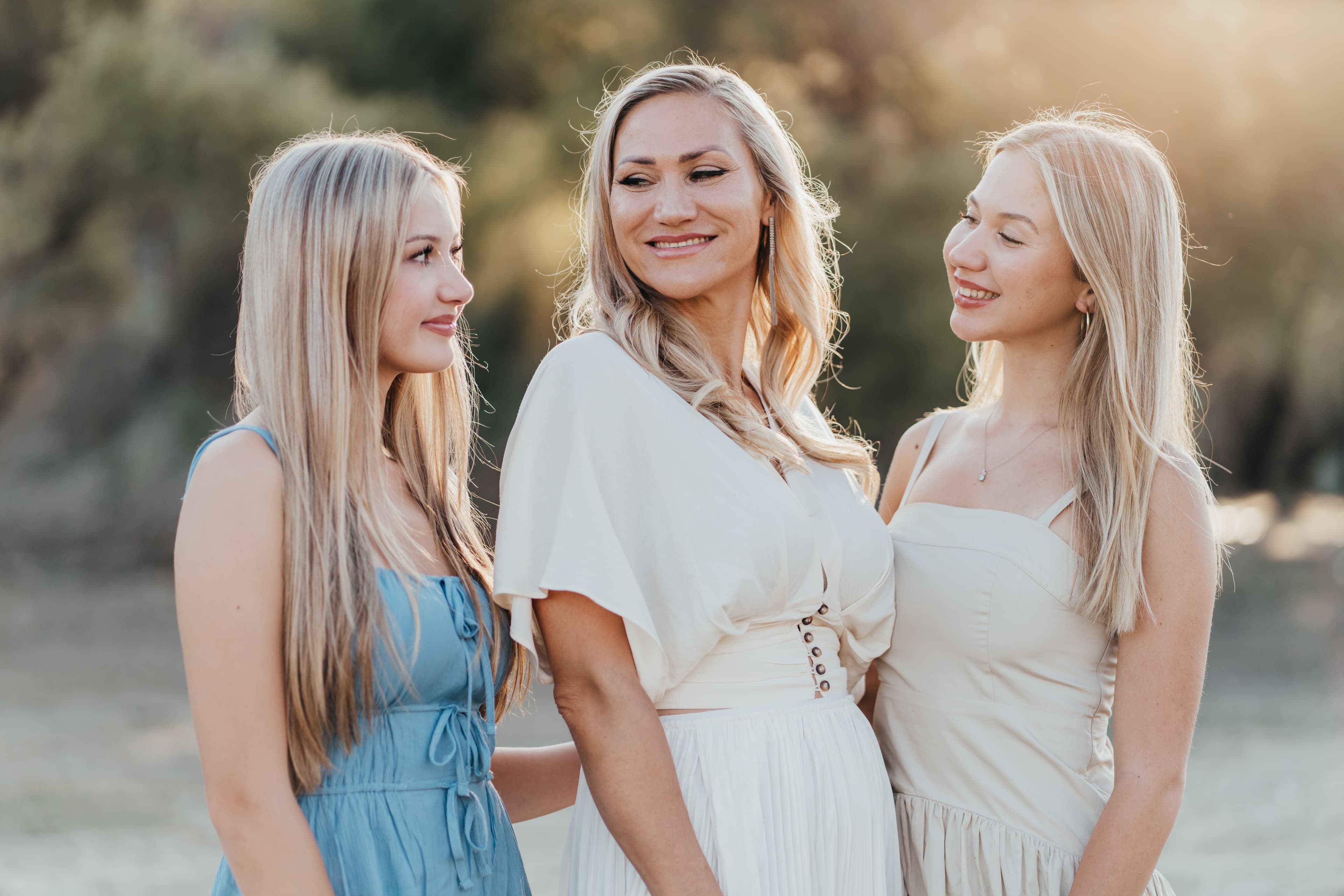 Three generations of women huddle together laughing in golden-hour light